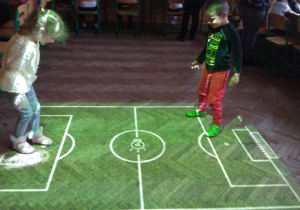Dzieci grają na magicznym dywanie w piłkę nożną.