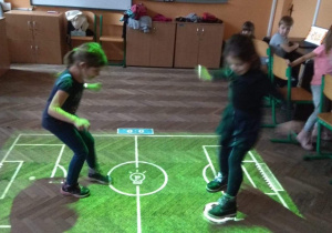 Dzieci grają na magicznym dywanie w piłkę nożną.