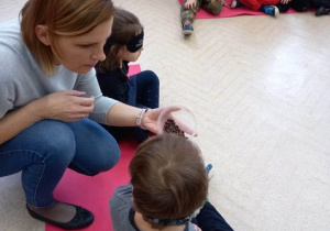 Dzieci, z zasłoniętymi oczami, próbują rozpoznać tajemniczy produkt za pomocą węchu.
