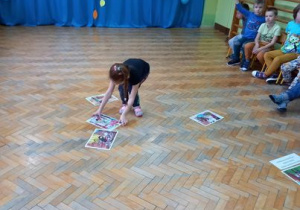 Dziewczynka układa obrazki na podłodze.
