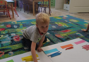 Dziecko dopasowuje kredki do odpowiedniego koloru.