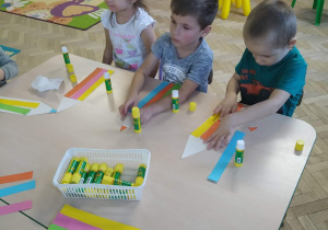 Dzieci wykonują kredkę z kolorowego papieru.