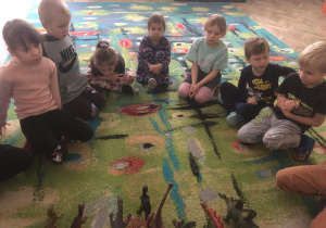 Dzieci oglądają figurki dinozaurów.