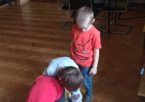 Dzieci stojąc jedno za drugim, podają sobie piłkę między nogami.