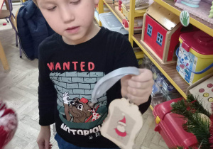 Chłopiec prezentuje własnoręcznie wykonaną ozdobę choinkową.
