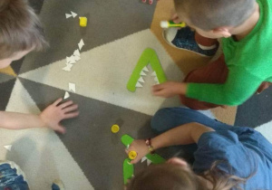 Dzieci przyklejają białe trójkąty - zęby w paszczy krokodyla - znak mniejszości lub większości.
