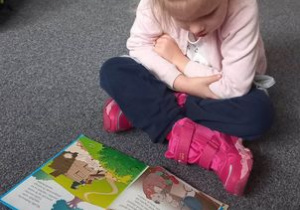 Dziewczynka ogląda książkę.
