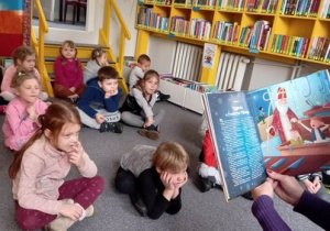 Pani bibliotekarka czyta dzieciom książkę.