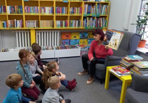 Pani bibliotekarka pokazuje dzieciom książkę.