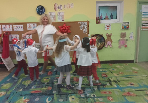 Dzieci tańczą w kółeczku z kolorowymi wstążkami.