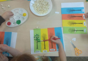 Dzieci malują farbami popcorn - kwiaty, liście lub owoce na drzewach.
