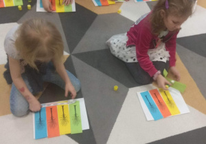 Dzieci przyklejają na kartonie odpowiednie kolory kartek z konturami drzew: zielony - wiosna, żółty - lato, pomarańczowy - jesień, niebieski - zima.