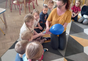 Dzieci pompują balony pompką.