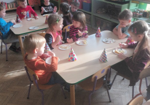 Dzieci jedzą słodki poczęstunek urodzinowy.