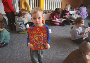 Chłopiec pokazuje książkę o znajomości owoców i warzyw.