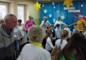 Babcie i Dziadkowie tańczą "Kaczuszki" w asyście swoich wnuków.