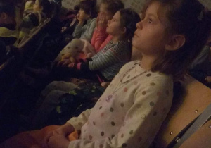 Dzieci siedzą i z zaciekawieniem oglądają przedstawienie.