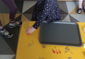 Dziewczynka sprawdza działanie magnesu na papierowych wycinankach..