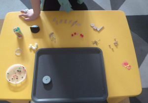 Dzieci sprawdzają, jakie przedmioty leżą na stoliku.