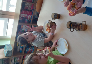 Dzieci jedzą własnoręcznie przygotowaną pizzę.