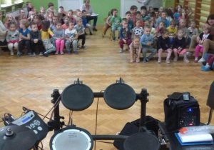 Dzieci biorą udział w koncercie, na którym główną rolę gra perkusja elektroniczna.