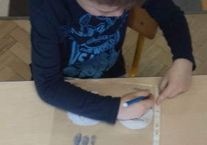 Chłopiec rysuje mazakiem na koszulce foliowej wodę.