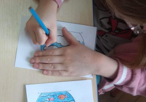 Dziewczynka koloruje obrazki przedstawiające obieg wody w przyrodzie.