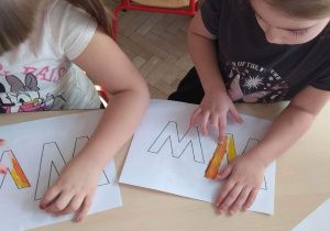 Dzieci malują plasteliną, wypełniając kontur litery W.