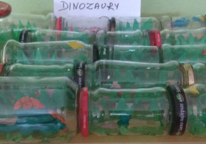 Wystawa dinozaurów wykonanych z plasteliny i umieszczonych w słoikach.