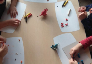 Dzieci modelują z plasteliny dinozaury.