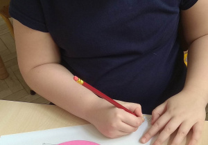 Dziewczynka podpisuje się pod swoją pracą - ptaszek z kół origami.