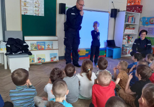 Dzieci słuchają funkcjonariusza Policji.