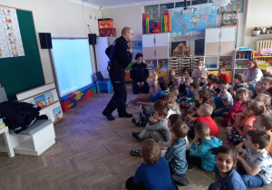 Dzieci słuchają funkcjonariusza Policji.