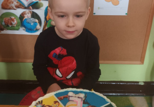 Chłopiec siedzi przy swoim urodzinowym torcie.