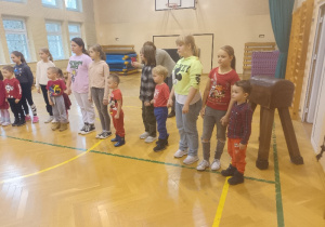 Dzieci z uczniami szkoły stoją dumnie na sali gimnastycznej.