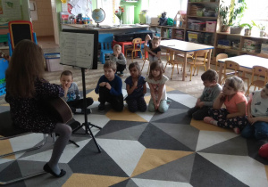 Dzieci słuchają utworów granych na gitarze.