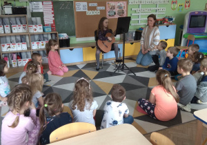Dzieci słuchają utworów granych na gitarze.
