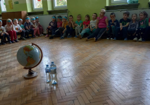 Na podłodze stoi globus i butelki wody.