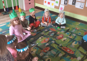 Dzieci siedzą na dywanie z wiosennymi opaskami.