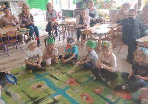 Dzieci siedzą na dywanie z instrumentami.