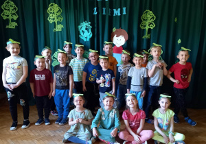 Dzieci z grupy zielonej stoją na tle dekoracji.