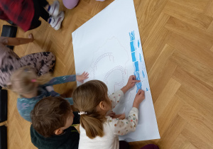 Dzieci tworzą wspólny plakat.