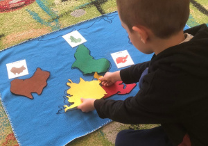 Chłopiec układa sylwetę kontynentu na mapie świata.
