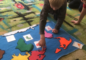 Chłopiec wskazuje Europę na mapie świata.