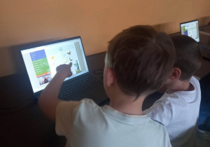 Dzieci siedzą przed komputerem.