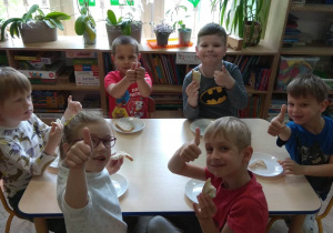 Dzieci jedzą samodzielnie przygotowane kanapeczki z serkiem smakowym.