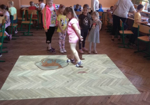 Dzieci korzystają z magicznego dywanu. Zabawa "Na tropie zwierząt".