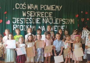 Dzieci stoją na scenie i deklamują wiersz dla Rodziców.