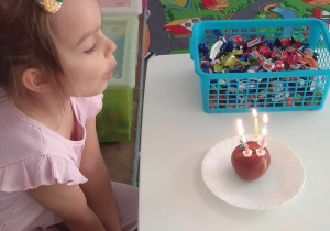 Dziewczynka zdmuchuje świeczki na torcie z jabłuszka.