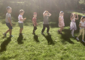 Dzieci wykonują ćwiczenia w ogrodzie przedszkolnym.